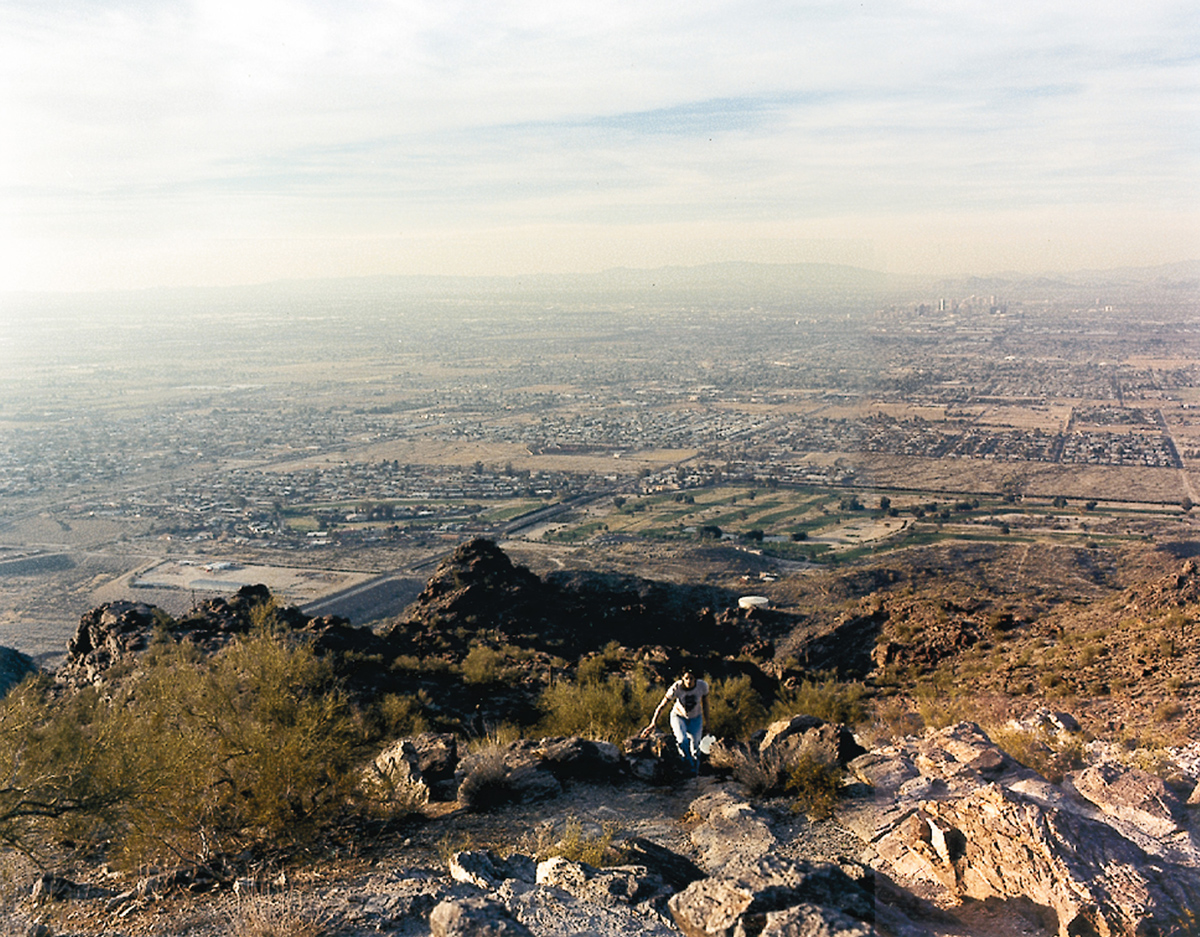 A 2000 photograph by artist Justine Kurland entitled “The City” depicting a woman climbing in the hills above an urban area. 