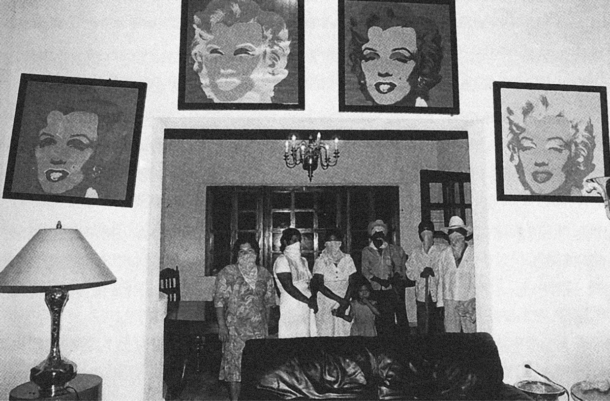 A 1994 photograph by photojournalist Omar Meneses of Zapatista rebels standing in the home of the owner of Finca Liquidámbar, a coffee plantation in the Ángel Albino Corzo province of Chiapas. Their faces are partially covered by handkerchiefs and four images of Marilyn Monroe by Andy Warhol are visible in the foreground.