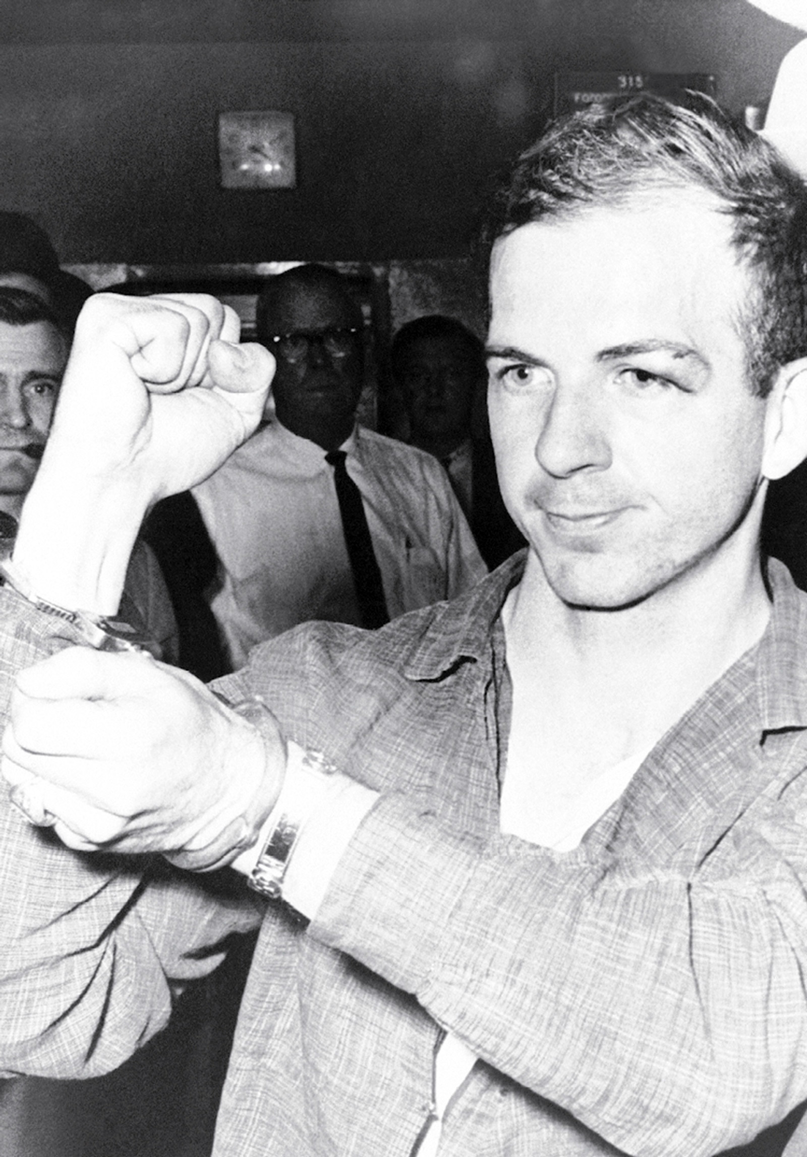 A photograph of Lee Harvey Oswald in handcuffs. 