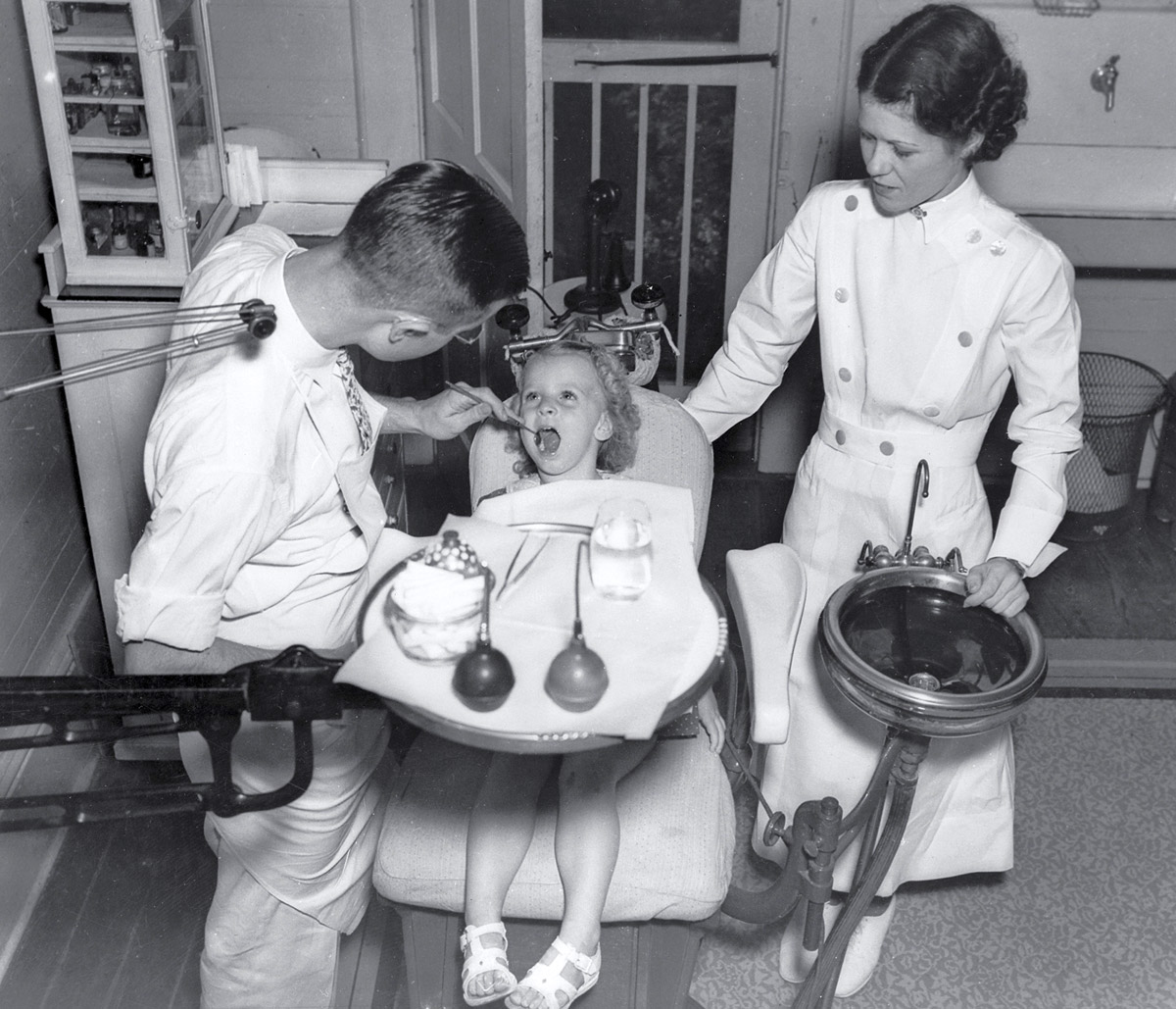 A photograph circa 1942 of a dentist examining a child’s teeth in New Orleans. 