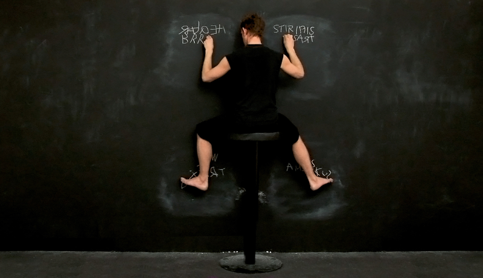 A photograph of a woman writing on a chalkboard using all four limbs. 
