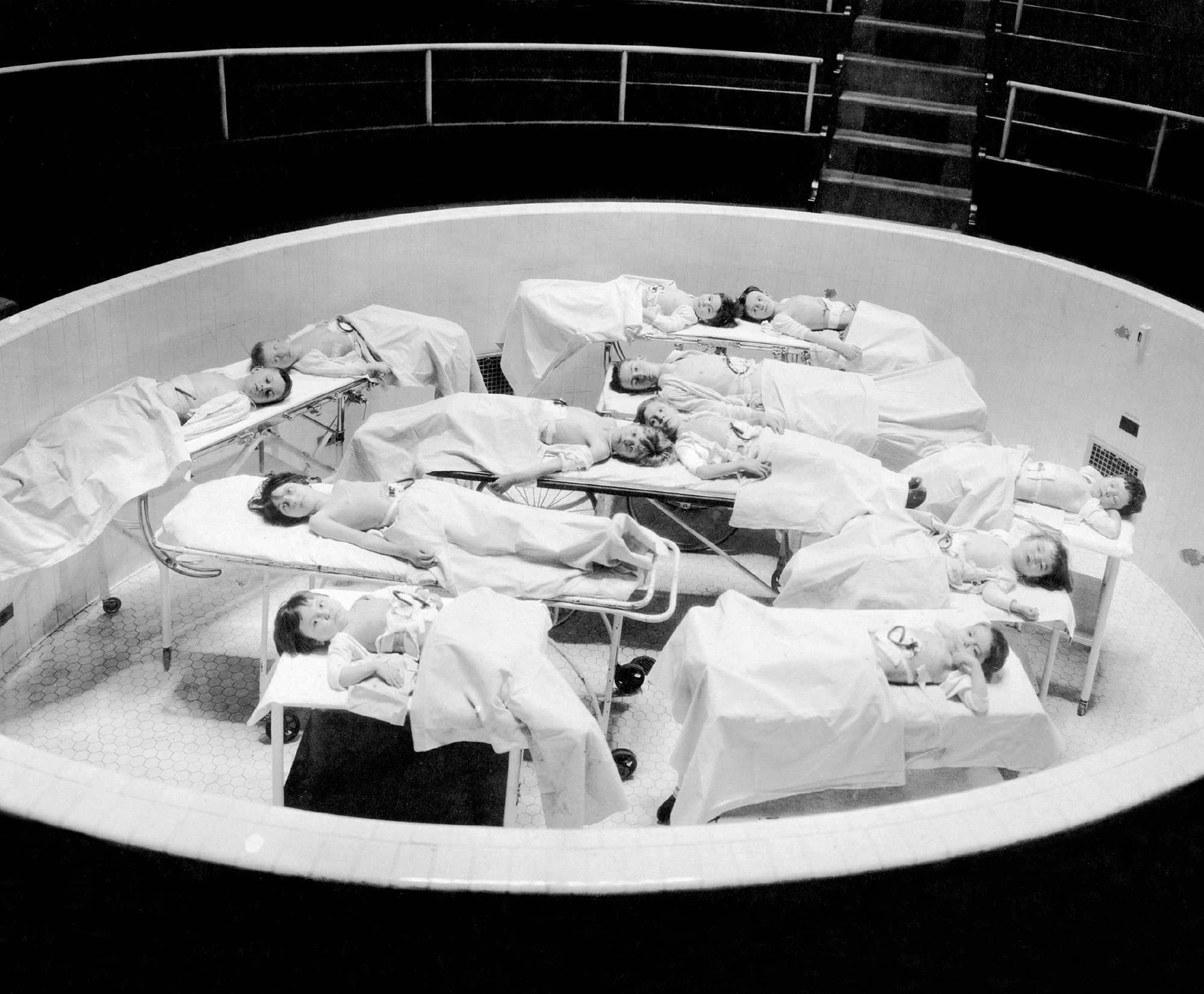 A photograph of children on hospital beds arranged in some kind of tank. 