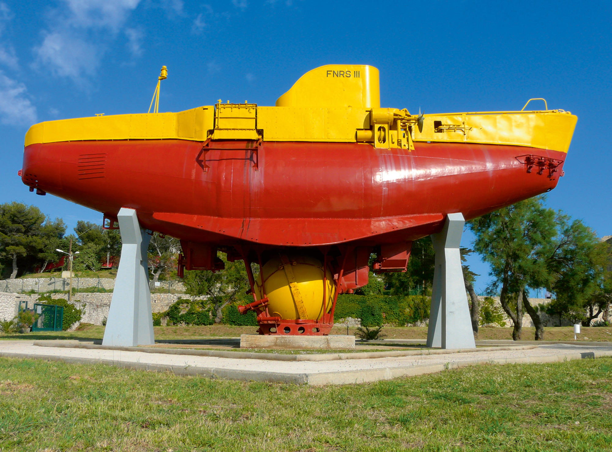 The French bathyscaphe FNRS 3, on display in Toulon. The vessel, based on a design by August Piccard, descended to a depth of 4,050 meters in nineteen fifty-four. Here it is seen painted red and yellow and propped on a boat stand. 