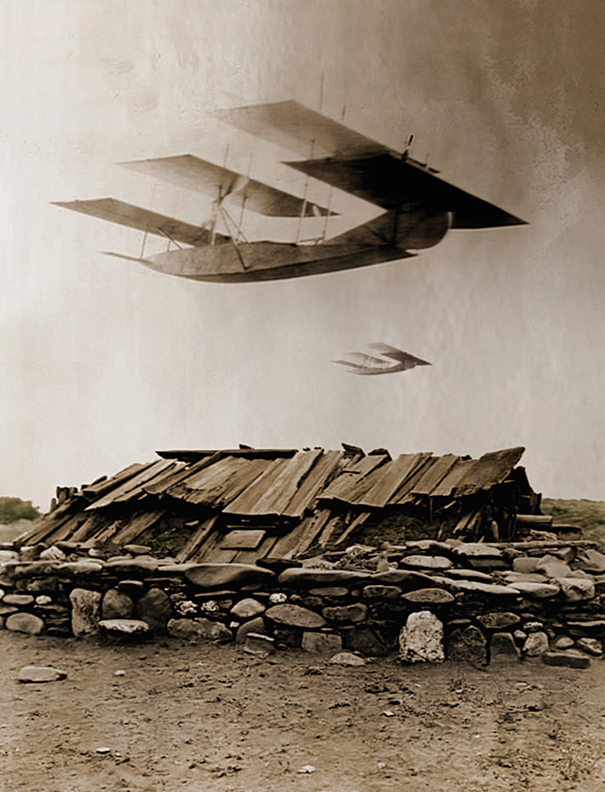 Oliver Wasow’s two thousand and nine artwork “Planes over Sweathouse.” It depicts some kind of three-winged plane over a wooden sweatlodge.