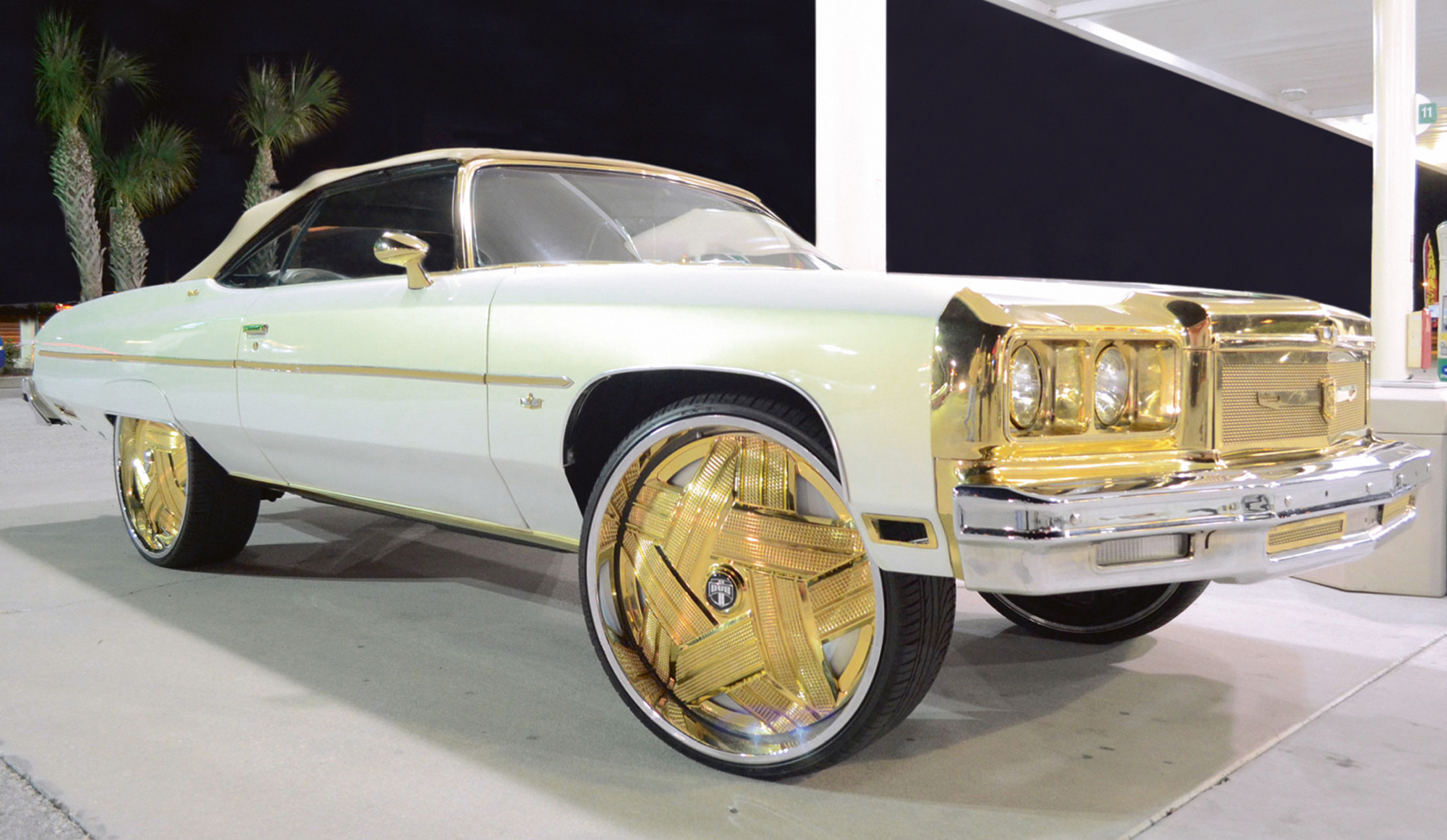 A photograph of an expensive car with ornate gold-rimmed wheels.