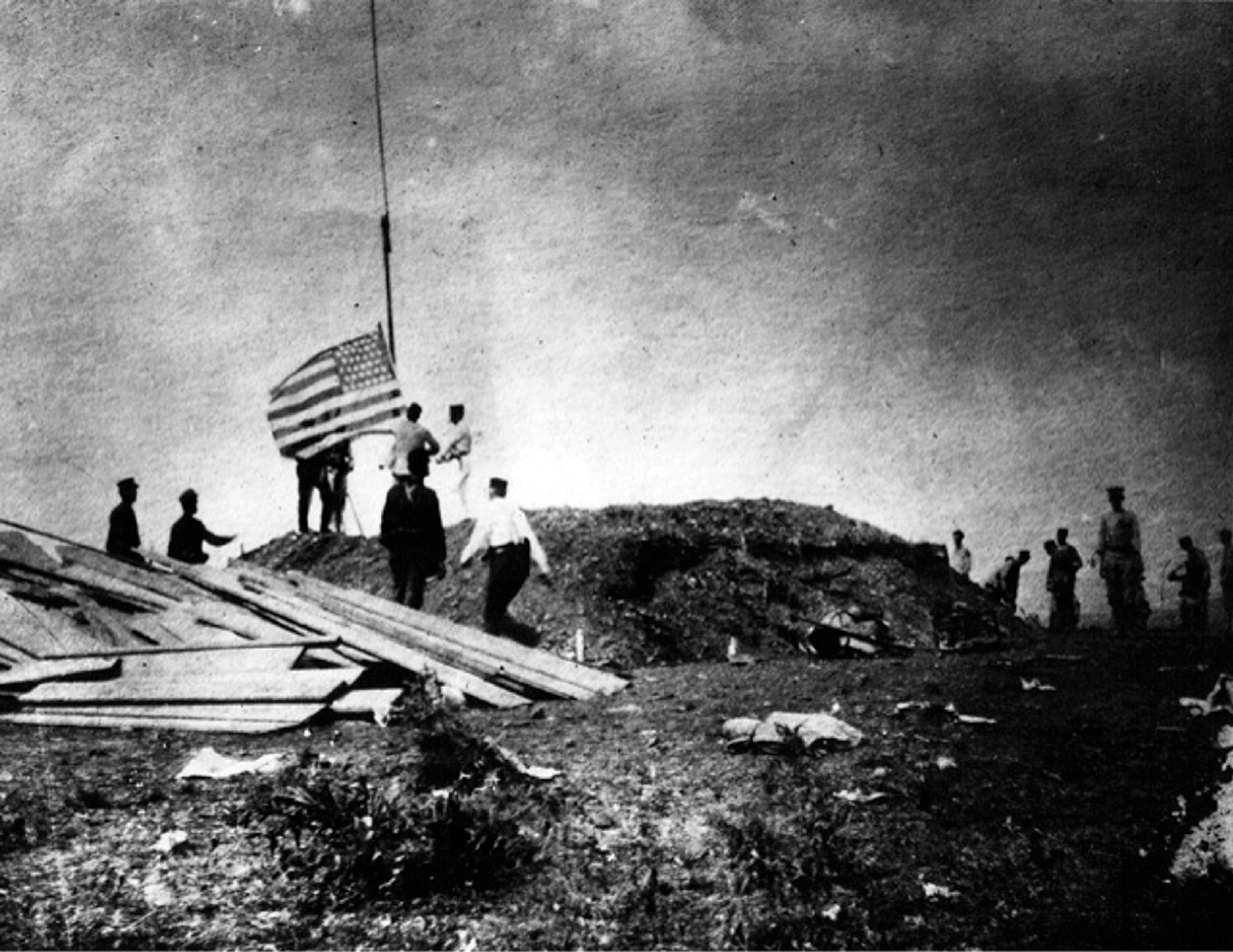 An eighteen ninety-eight photograph of United States soldiers raising the American flag at Guantánamo during the Spanish American war.