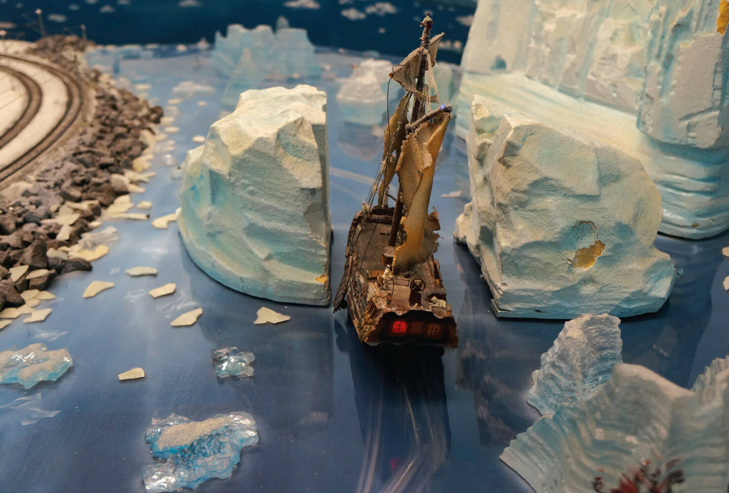 A photograph of a miniature sail boat navigating between two icebergs at the Miniatur Wunderland.