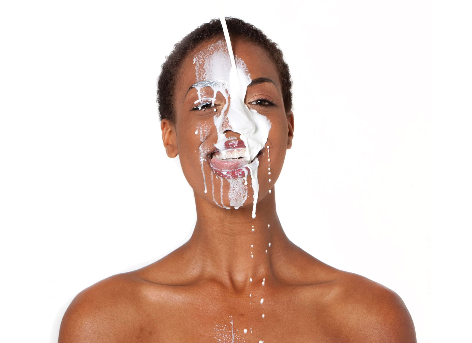A stock image of a woman with a stream of milk hitting her face.
