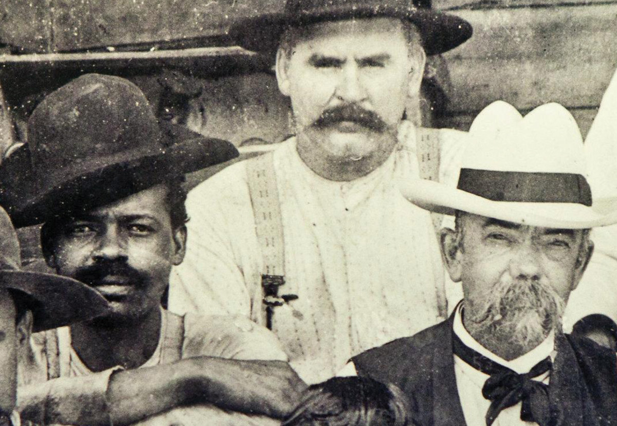 A late nineteenth century photograph of Jack Daniel at his distillery in Tennessee, sitting next to a man presumed to be Nearest Green, an enslaved man who helped teach Daniel how to make whiskey.