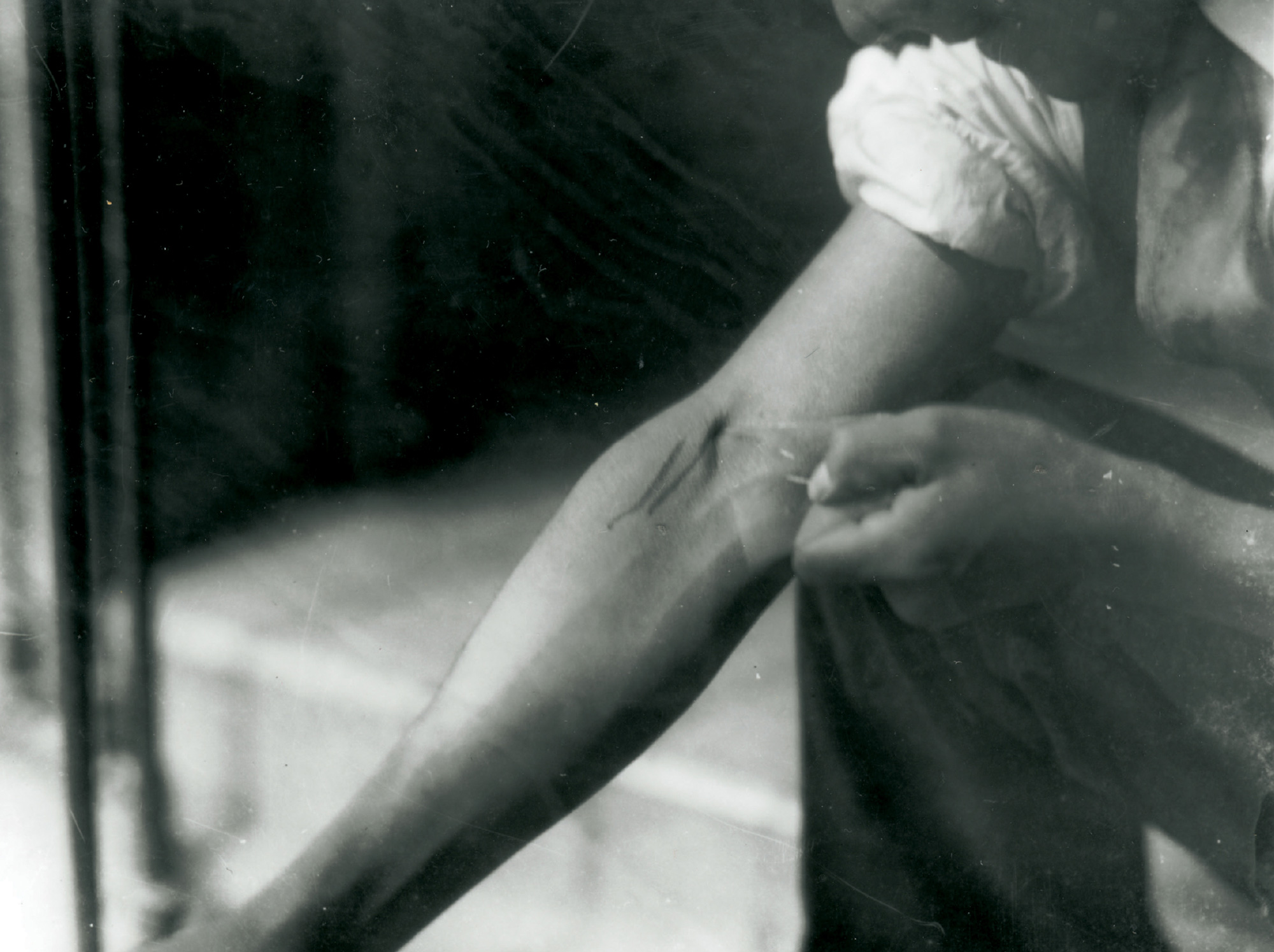 A photograph from the 1920s or 1930s depicting a man injecting drugs into his arm.