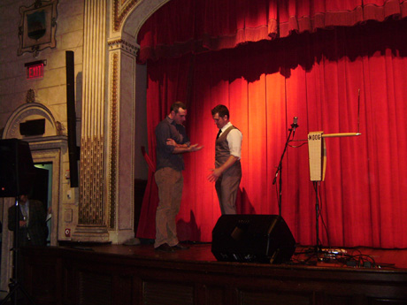 Jeff Grow, member of the Artifice Group puts a cigarette through Tom DeKay’s shirt.