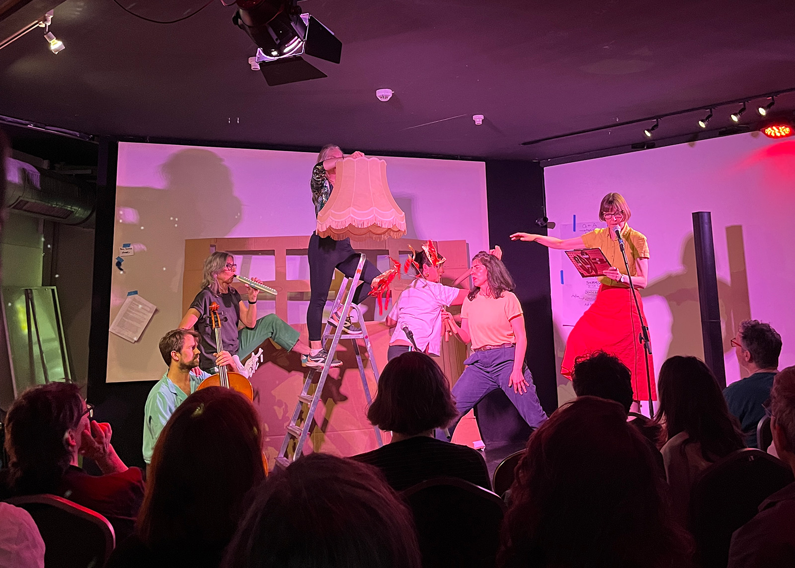 A photograph of the performers creating the text-to-voice conversion machine out of their bodies while Sally O’Reilly describes the machine’s operations to the audience.