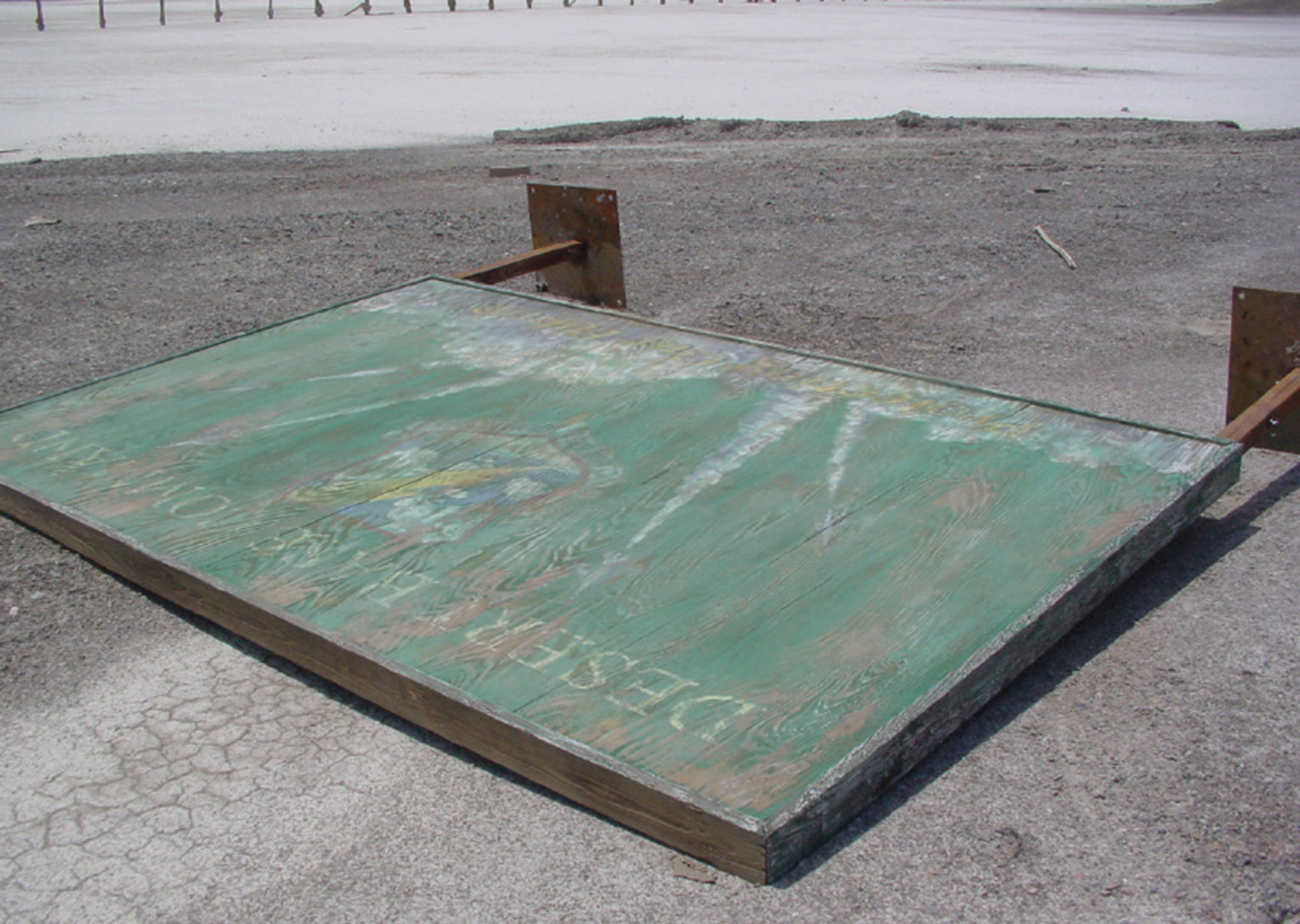 A photograph of a tipped-over wooden “Desert base command” sign.