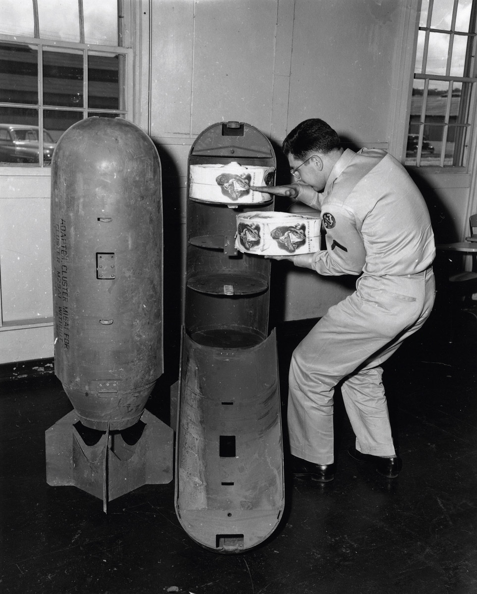 A photograph of leaflets being loaded into a specially adapted bomb canister, 1956.