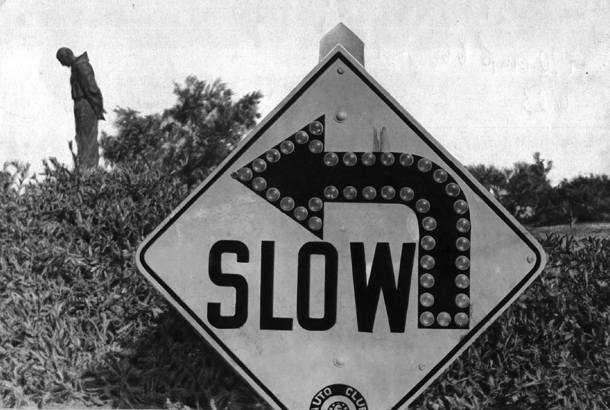 Black-and-white photograph of a slow turn sign.