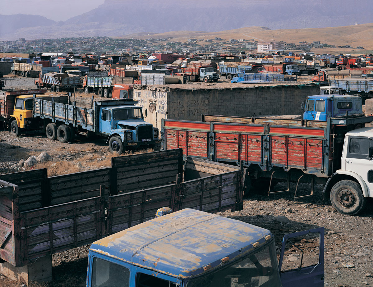 A photograph of trucks parked in a dumping ground at the Turkey-Iraq border.