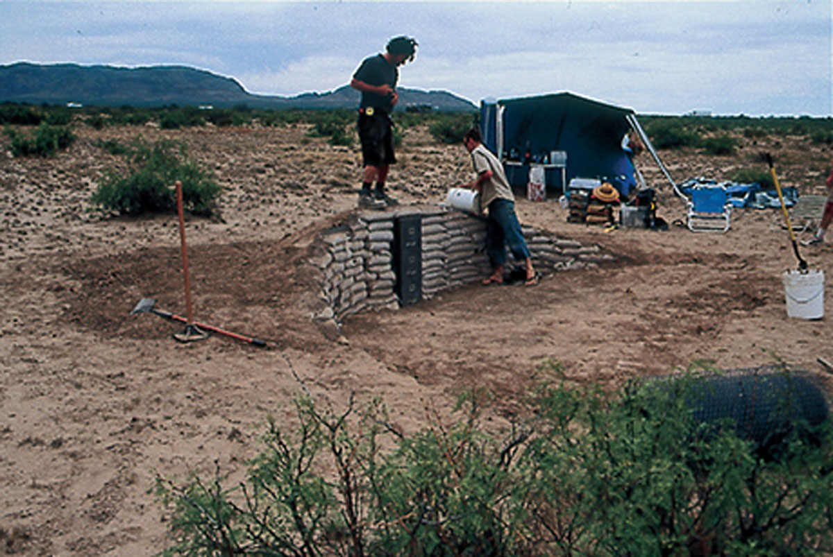 A photograph of the earthbag wall being coated in cement.