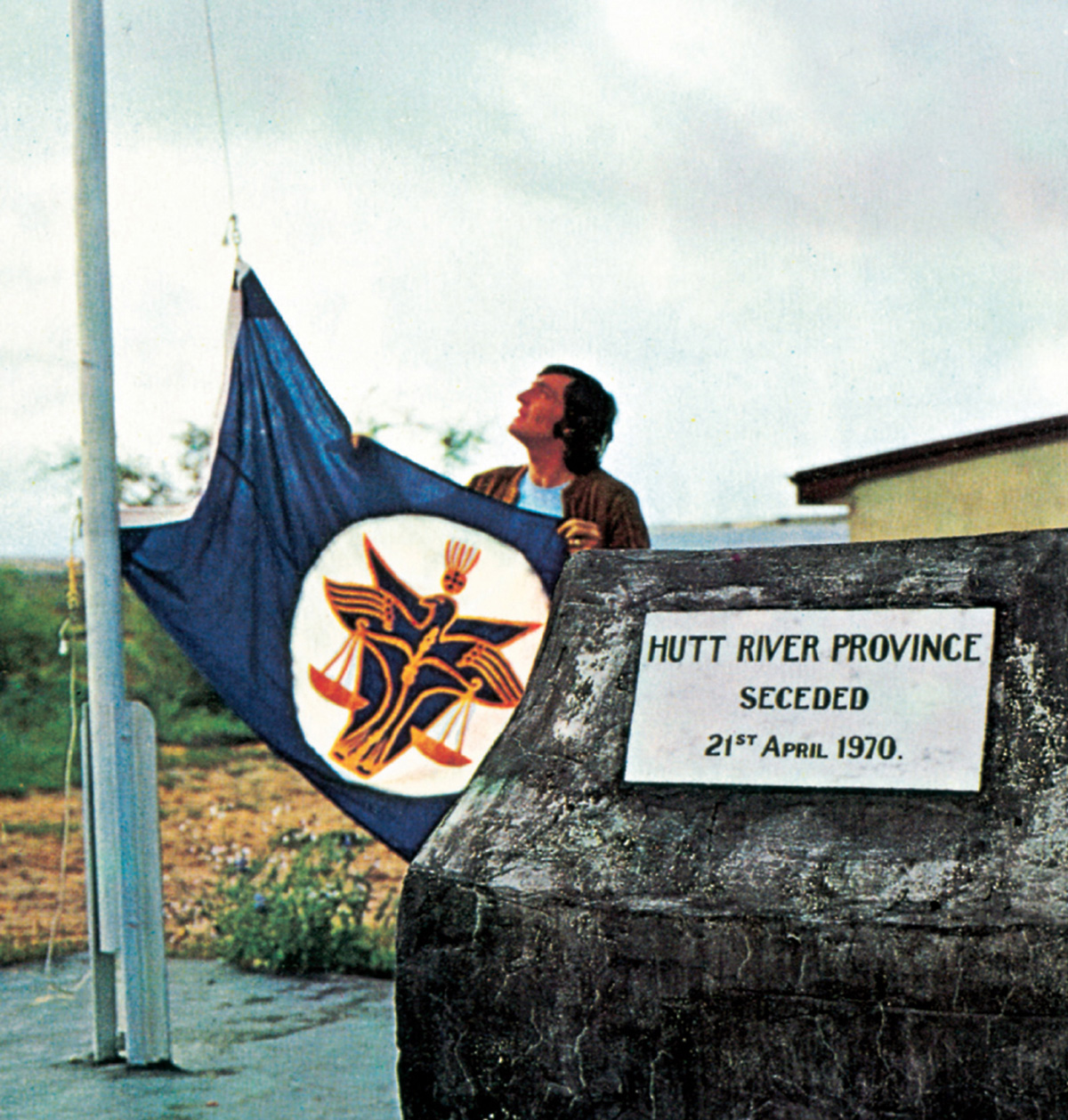 A photograph of a man raising the flag of the Hutt River Province Principality.