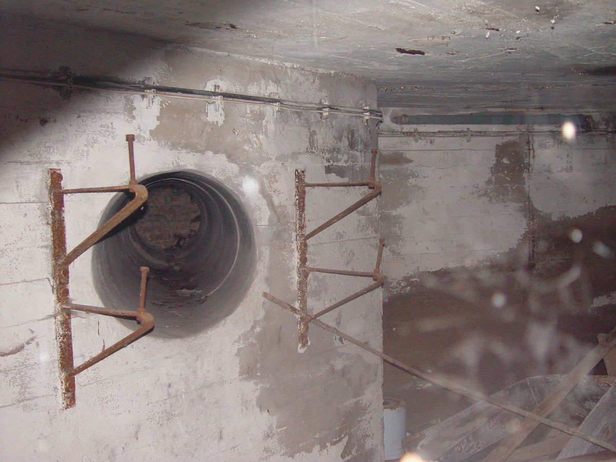 A photograph of a pipe in a concrete wall.