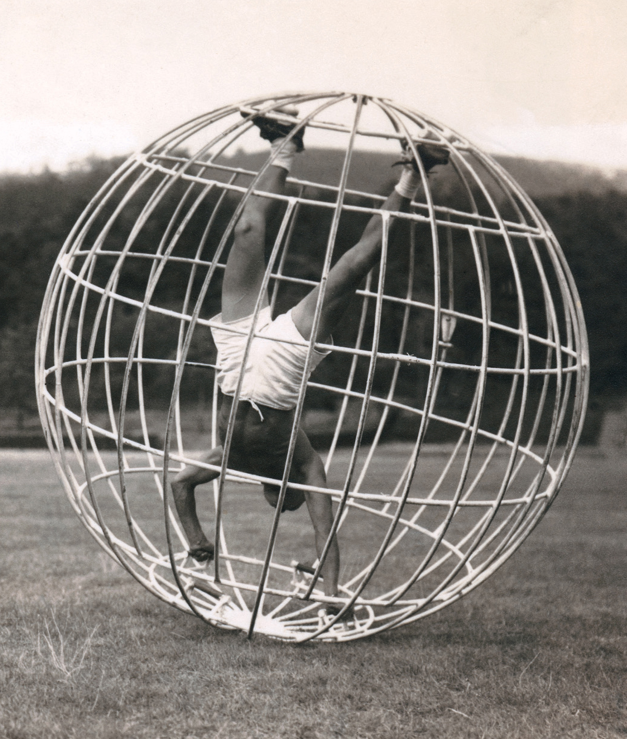 A photograph of a man balancing within a spherical cage, a device simulating the sensation of flight, and was one of the required exercises in the Primary Aviation Course. 