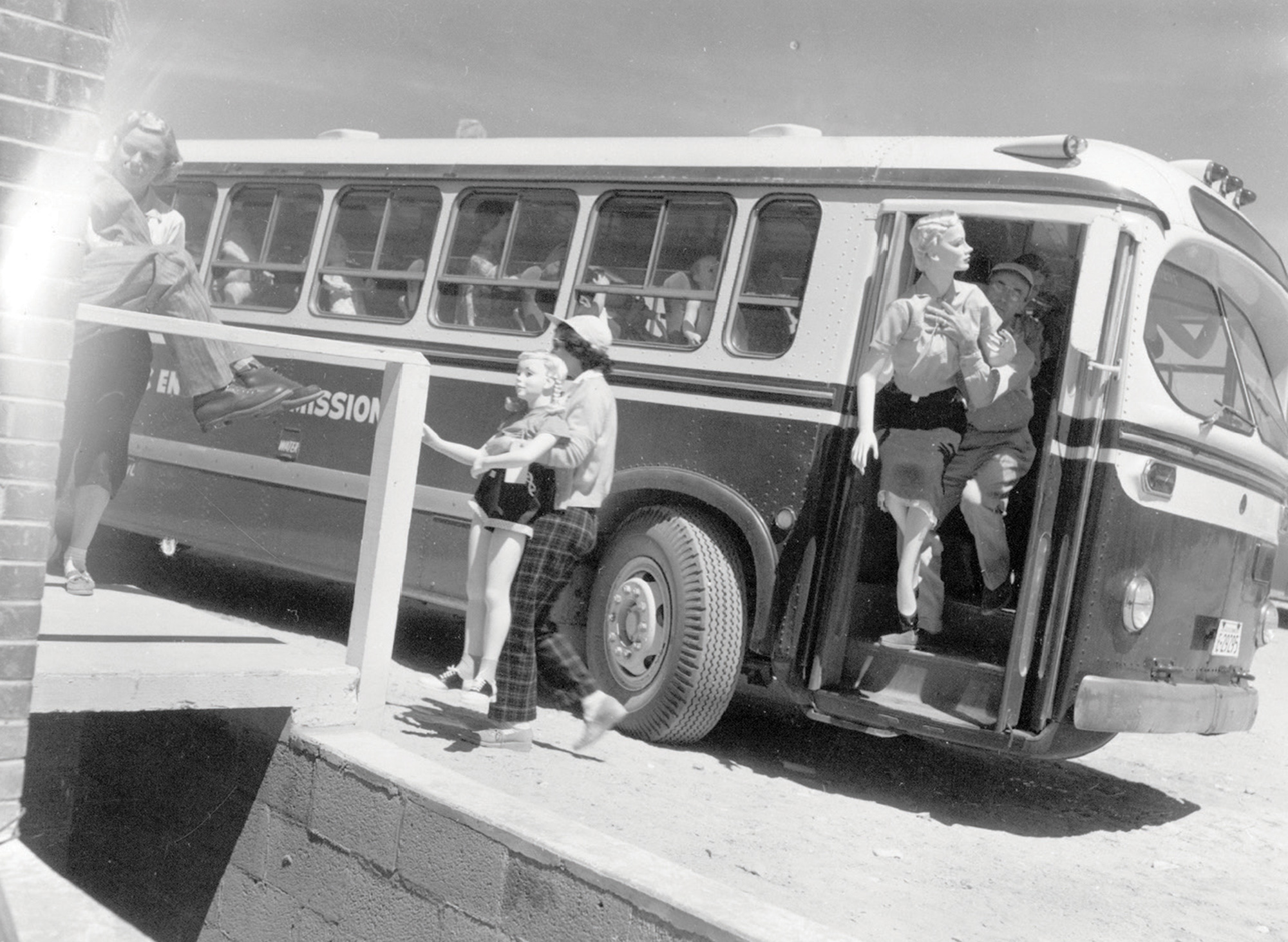 A photograph from Operation Cue, one of a series of tests conducted in the Nevada desert in 1955 in order to gauge the effects of nuclear bombs on various types of edifices. This photograph depicts a group of test dummies being taken off a bus in order to be placed in various model houses.
