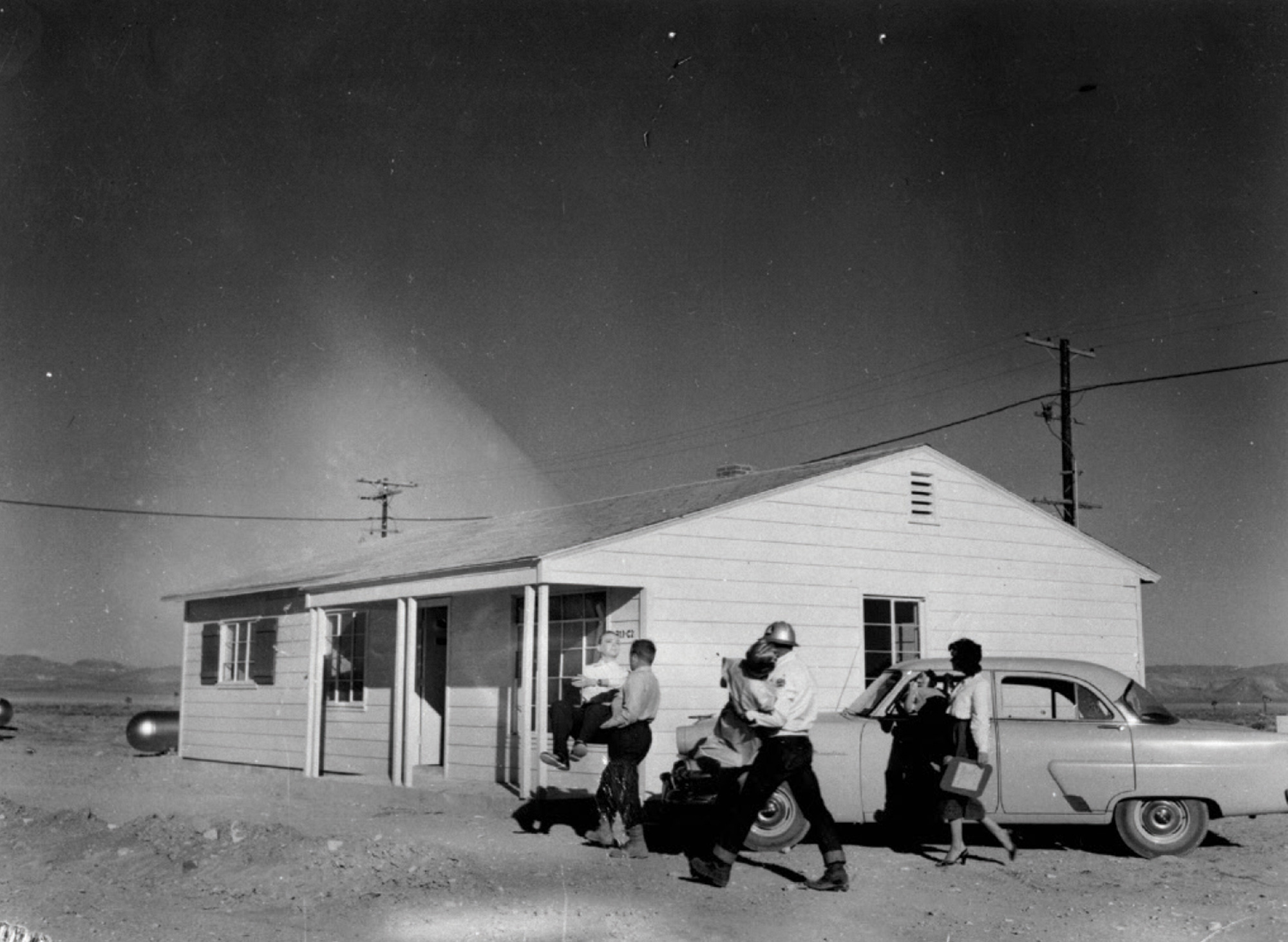 A photograph from Operation Cue depicting a group of test dummies being transported to a house.