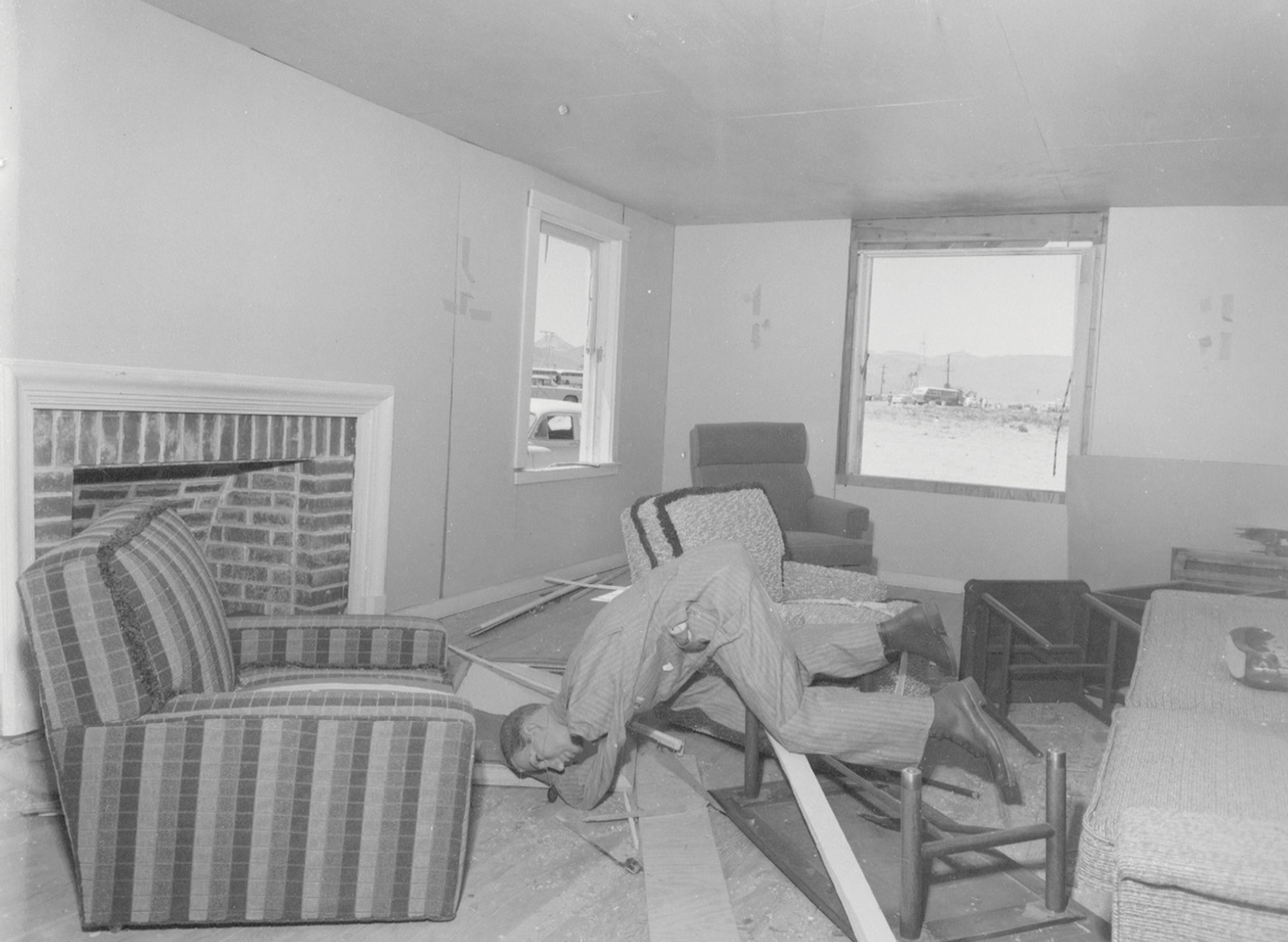 A photograph from Operation Cue depicting a damaged mannequin thrown to the ground as a result of the test explosion.