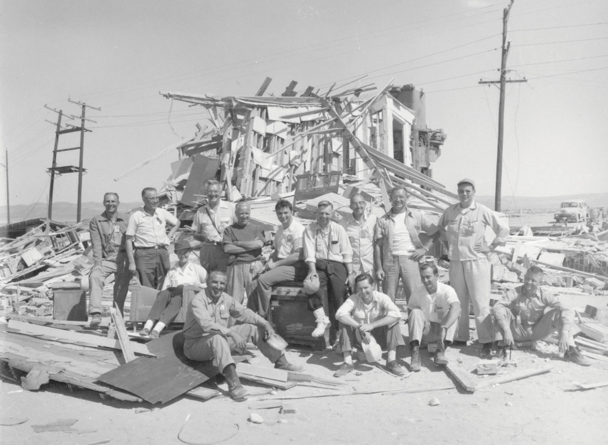 A photograph from Operation Cue depicting workers sitting on the rubble of a house.