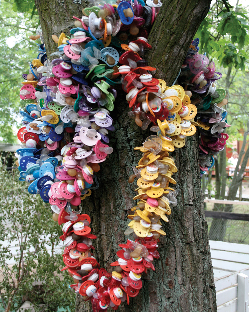 A photograph of a tree in Sweden festooned with pacifiers. 