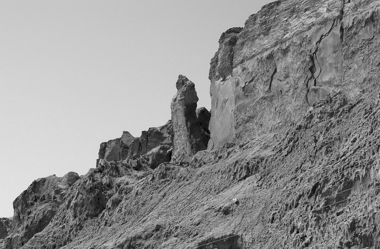 A photograph depicting the stark, salt-striated region of Mount Sodom with a solitary pillar signifying Lot’s wife. 