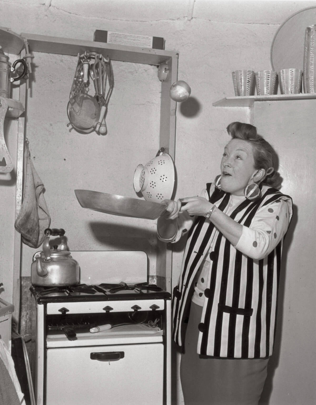 A photograph by Chris Ware from 25 June nineteen fifty six captioned, “British comedienne Beryl Reid tossing the Spanish onion on a Monday, as opposed to tossing the pancake on Pancake Tuesday.”