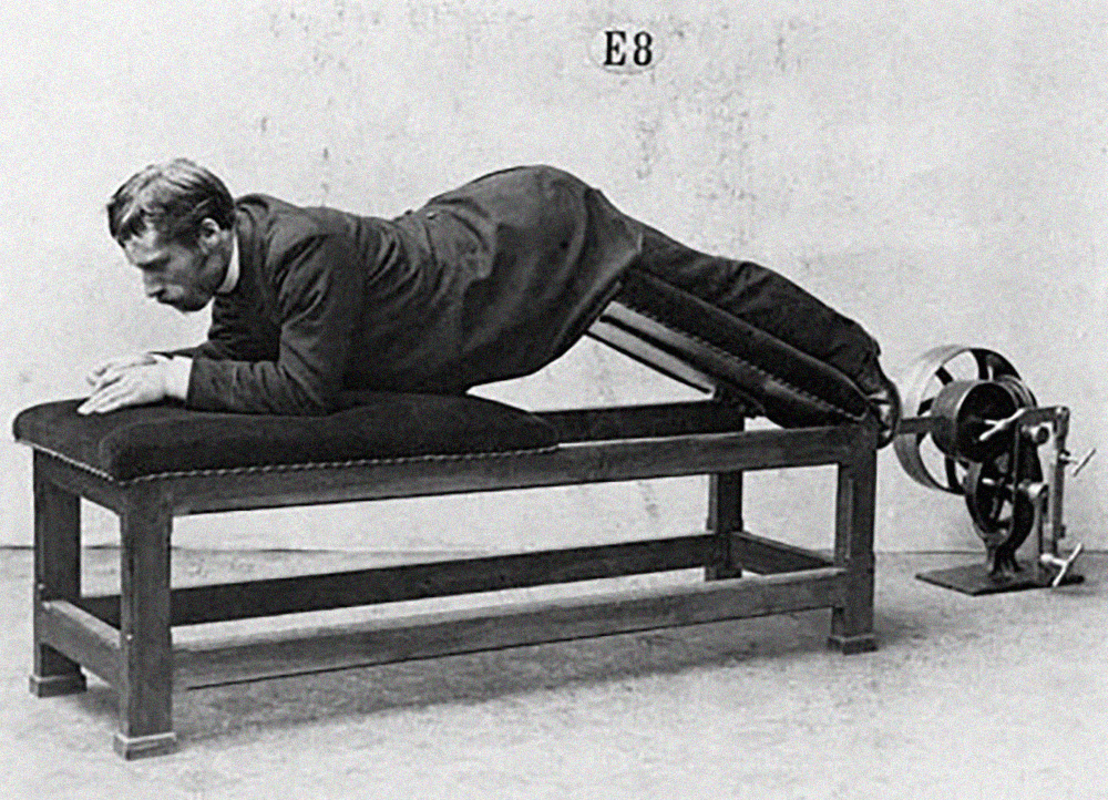 A nineteen-eighties photograph of a man in a suit reclining face down on a Zander exercise machine at the Zander Institute in Stockholm.