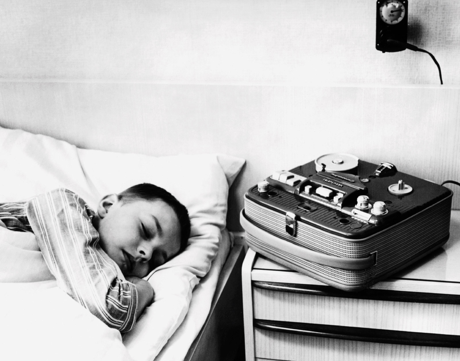 The front of this issue's postcard featuring a photograph of a boy asleep in bed with a tape player on the table beside him.