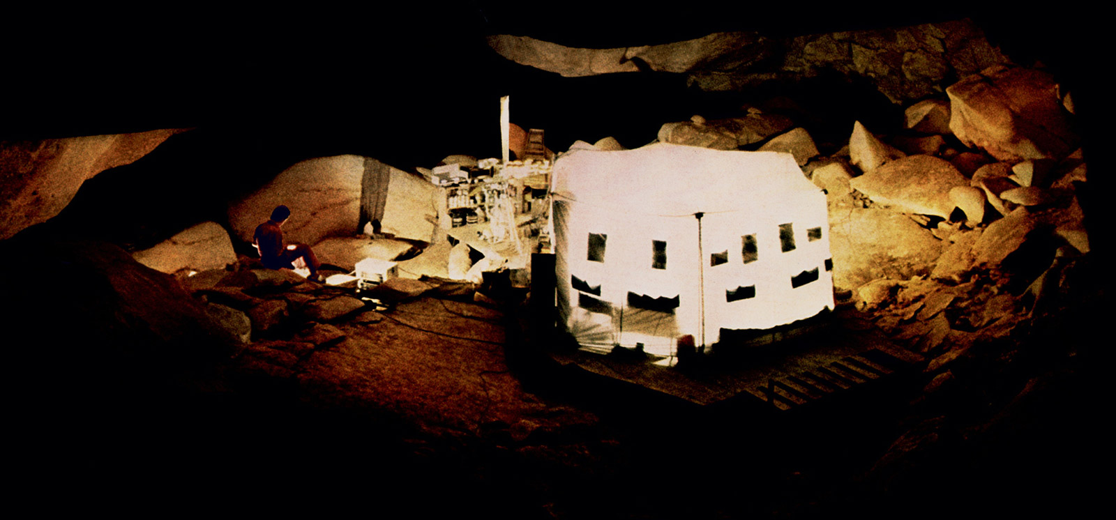 A nineteen seventy-two photograph of Michel Siffre’s tent in Midnight Cave, Texas, which glows with incandescent lights.