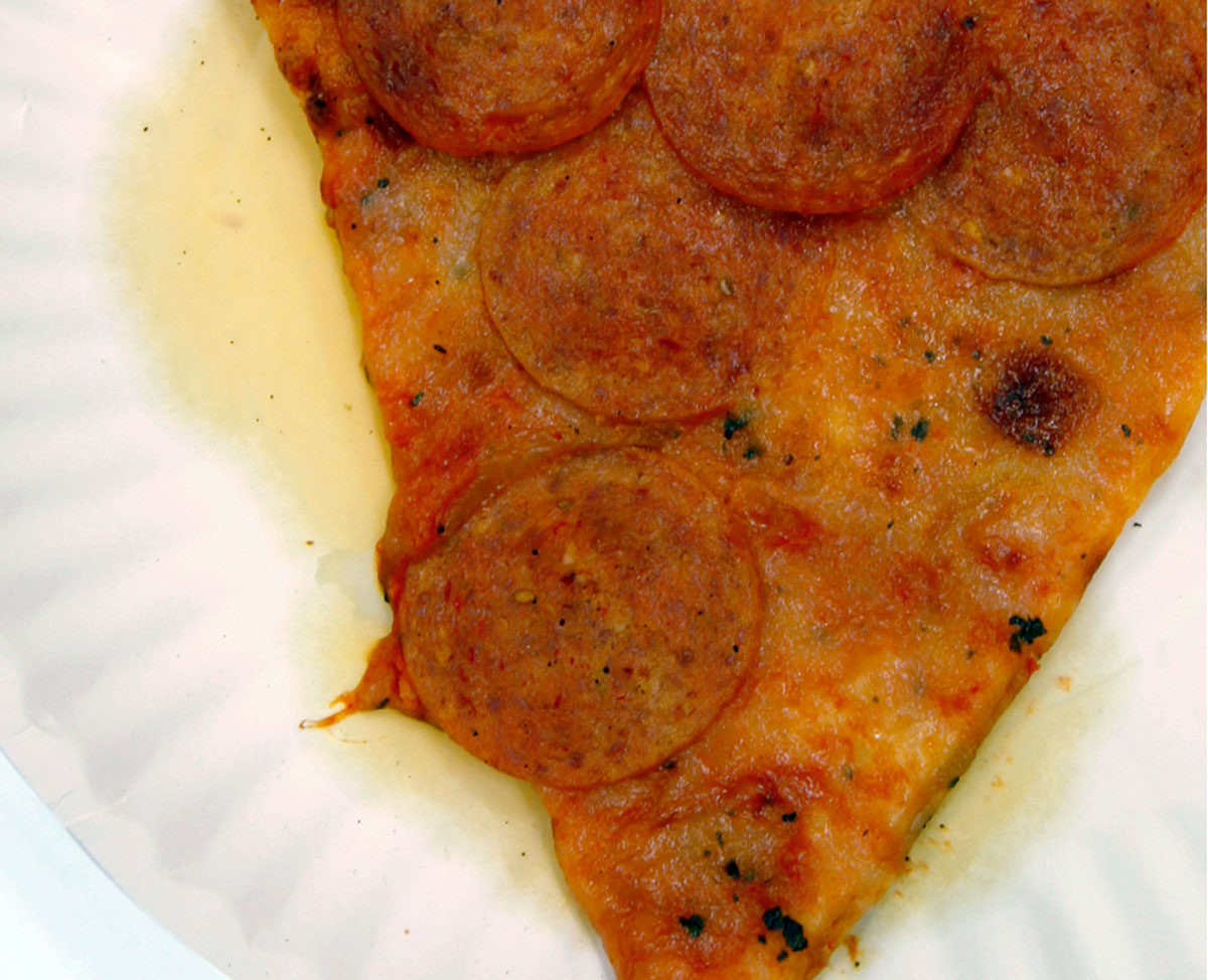 A photograph of a greasy slice of pepperoni pizza. 