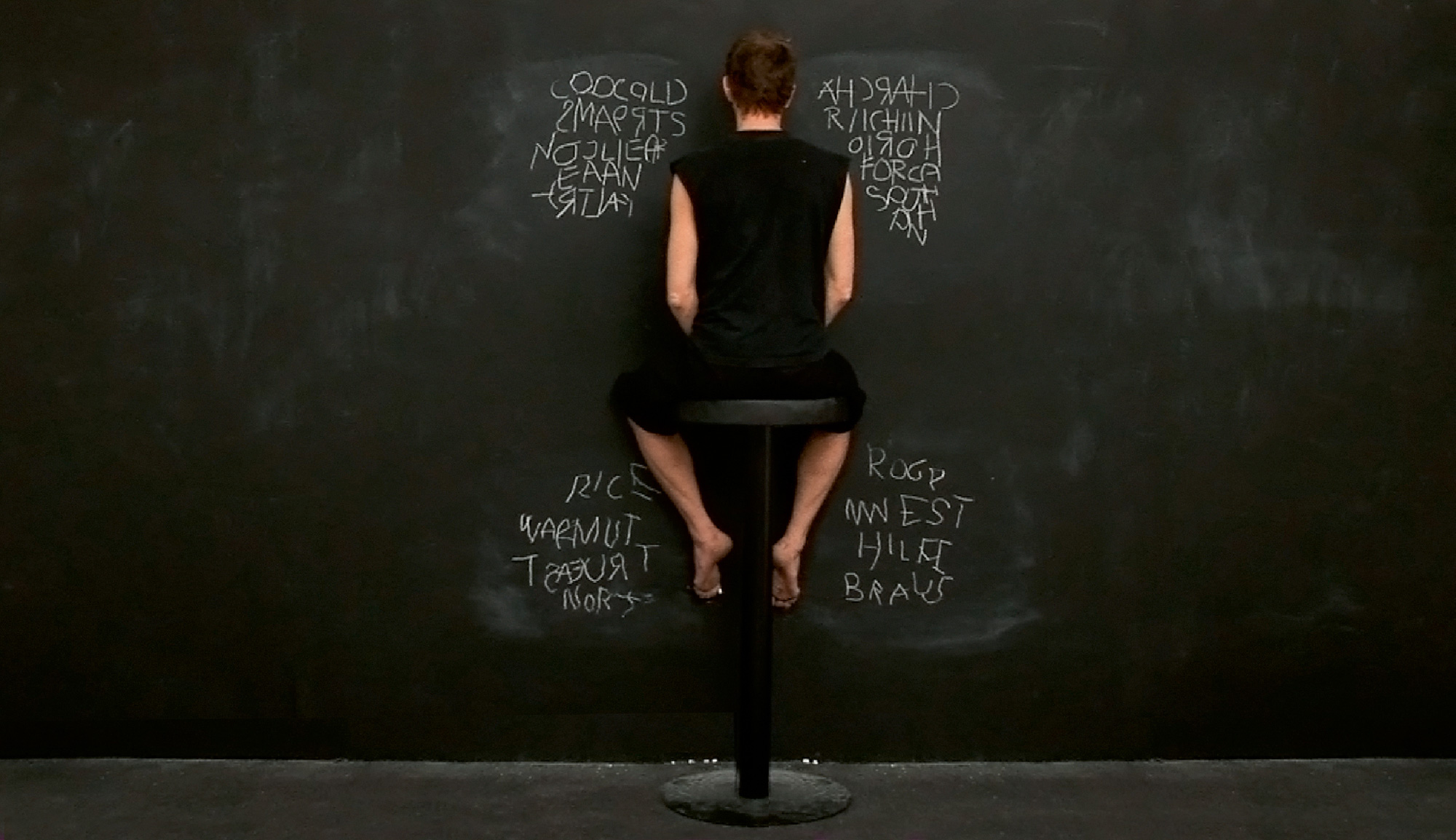 A photograph of a woman writing on a chalkboard using all four limbs. 