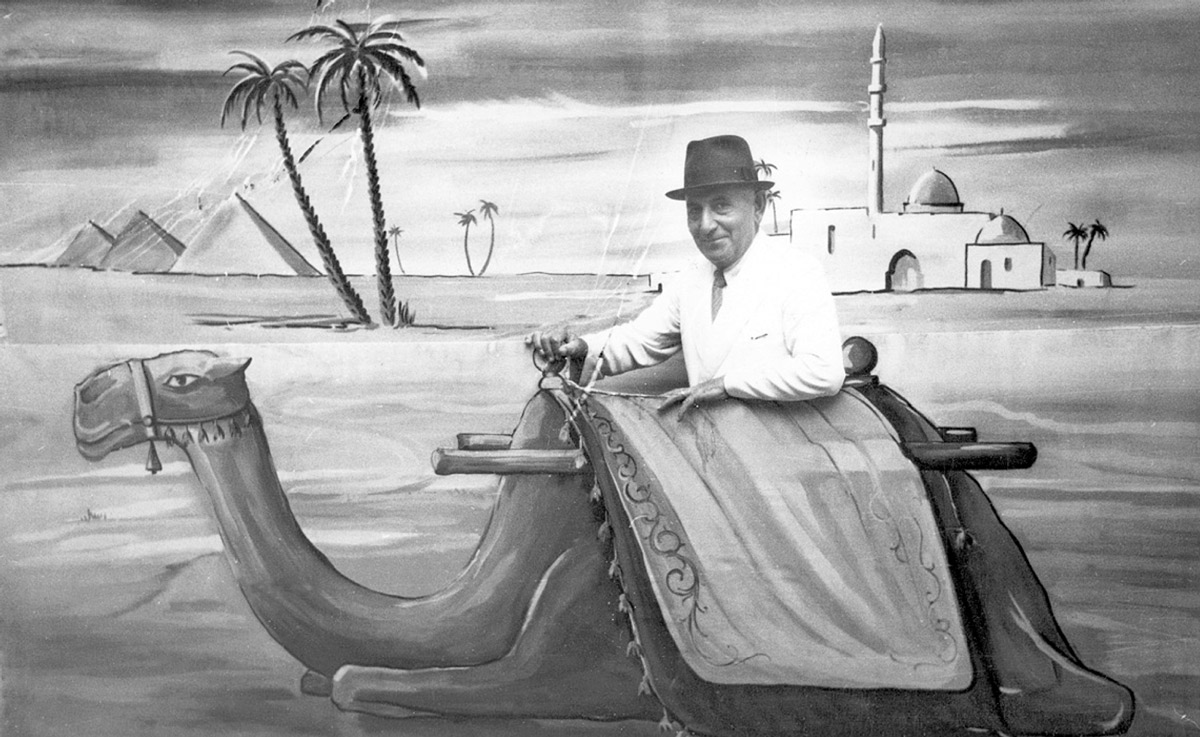 A photograph taken in 1958 in Zahleh, Lebanon, of “Baron Alinanan” posing behind a cutout of a camel.
