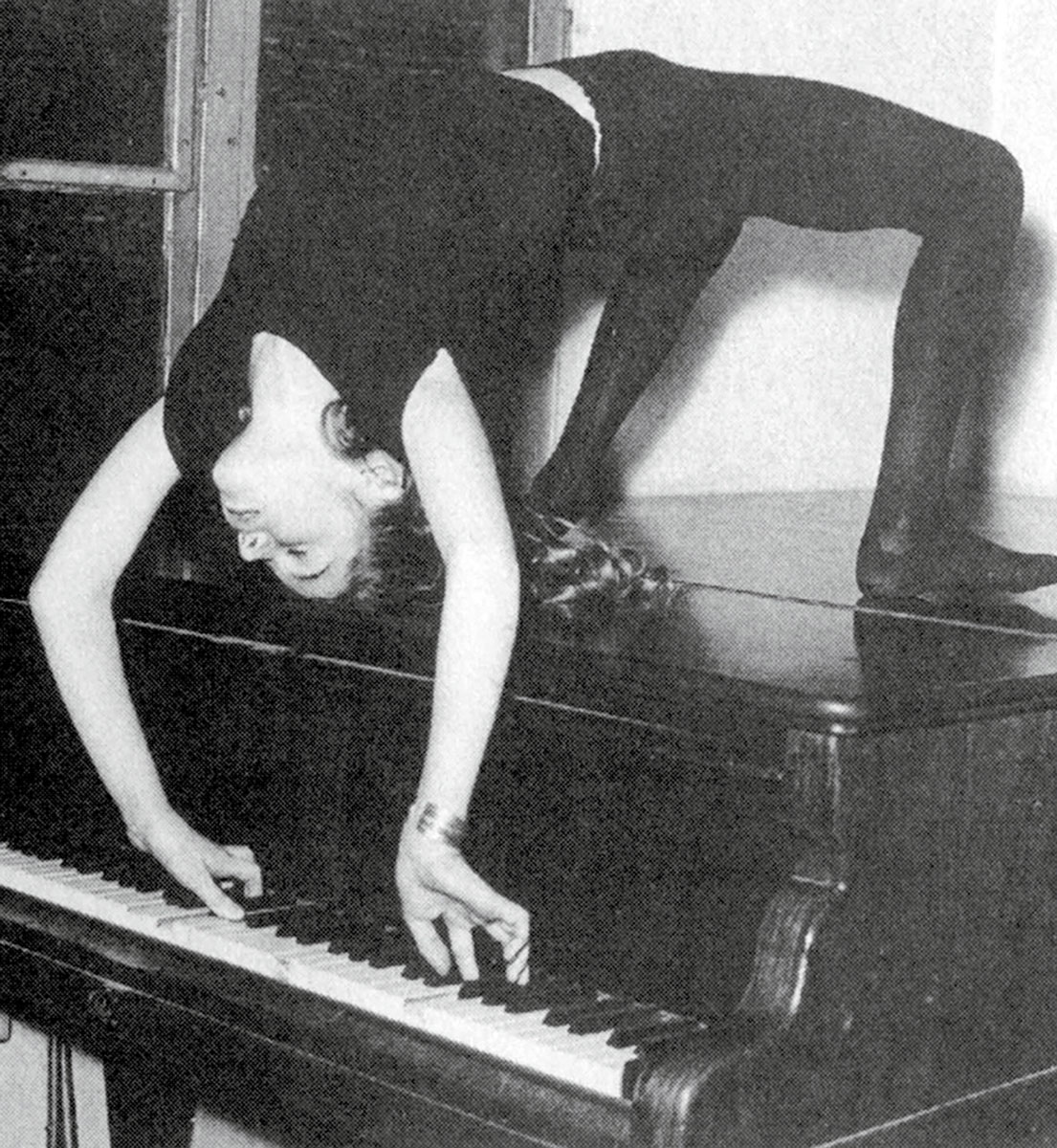 A photograph of Minou Drouet performing acrobatics while playing a sonata by Mozart, circa nineteen sixty. 