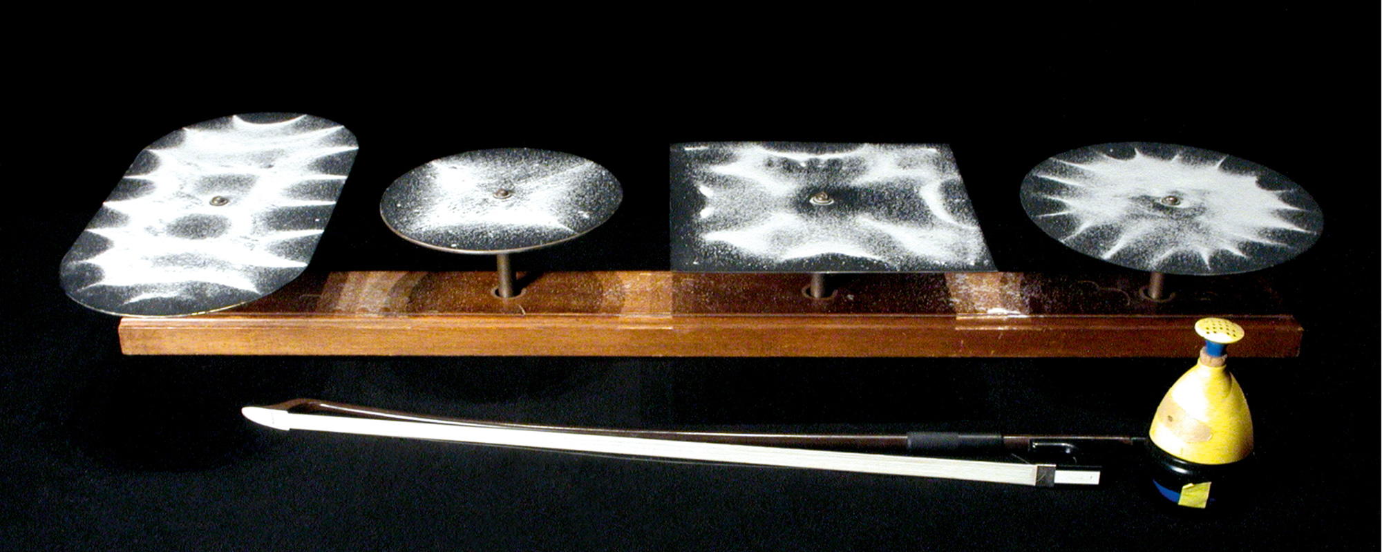 A photograph of Chladni plates showing different patterns of dispersion caused by their various shapes.