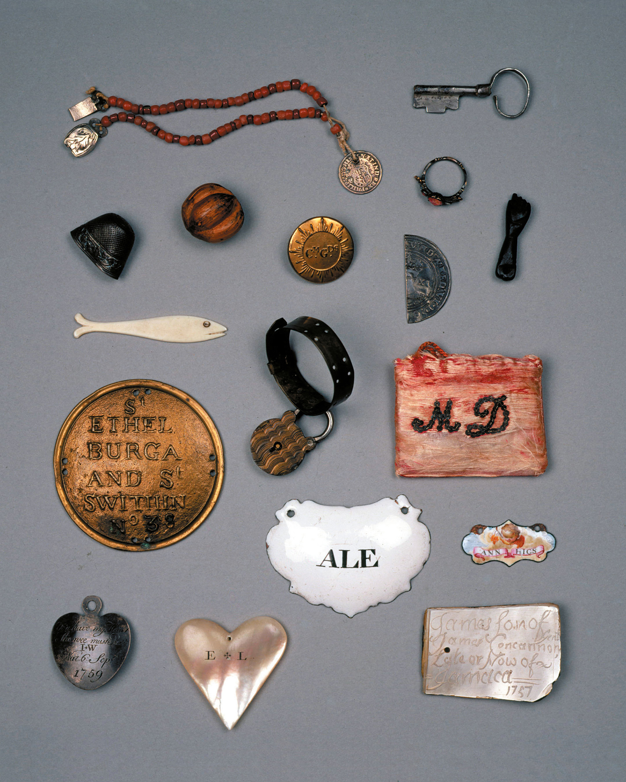A photograph of tokens left with children. They took a variety of forms and were often halved, as in the case of a coin at center-right, to allow for identification in the event that the mother later came to retrieve her child.