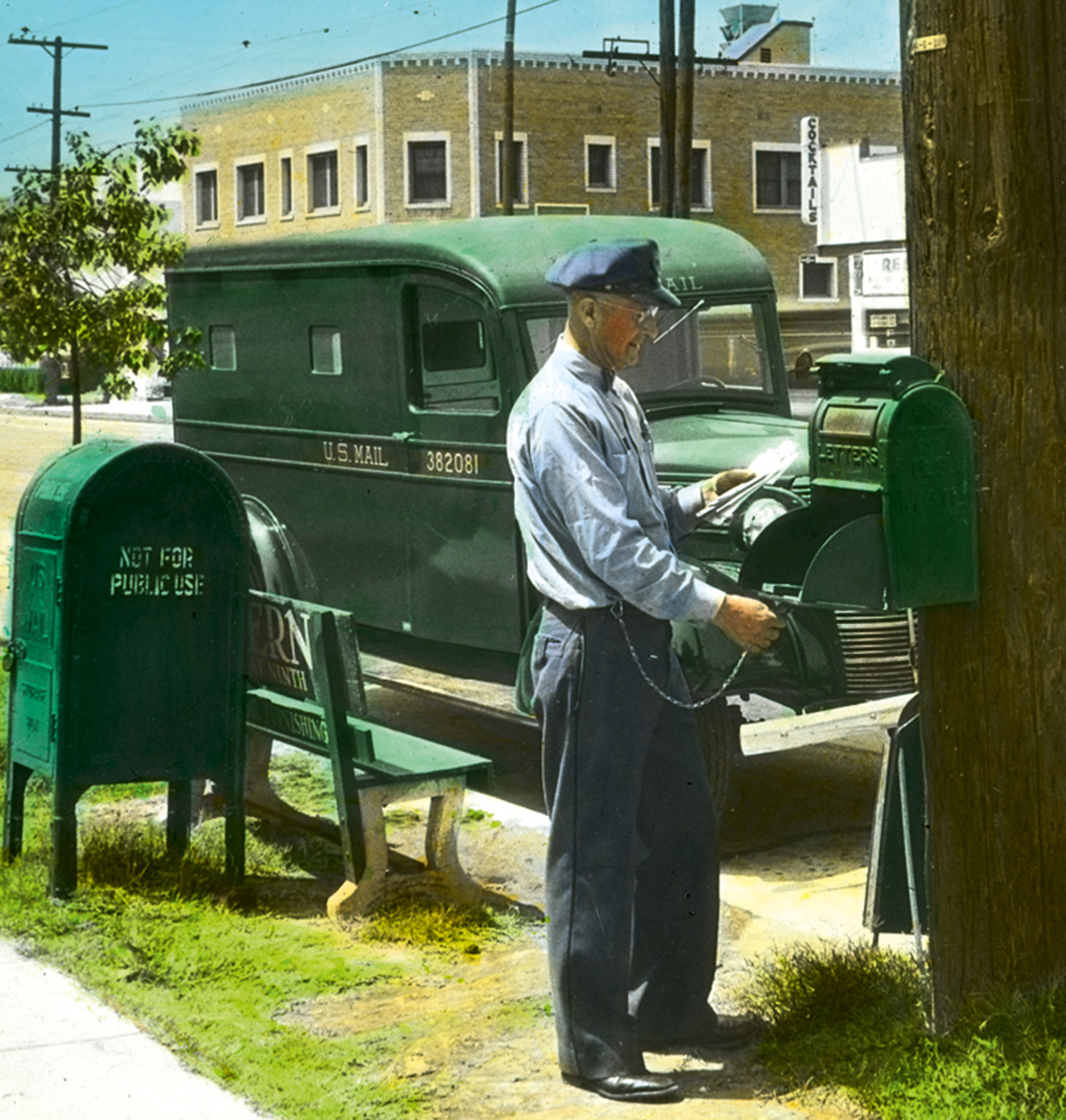 A circa nineteen forty-seven photograph of a letter carrier unlocking a mailbox mounted to a telephone pole.