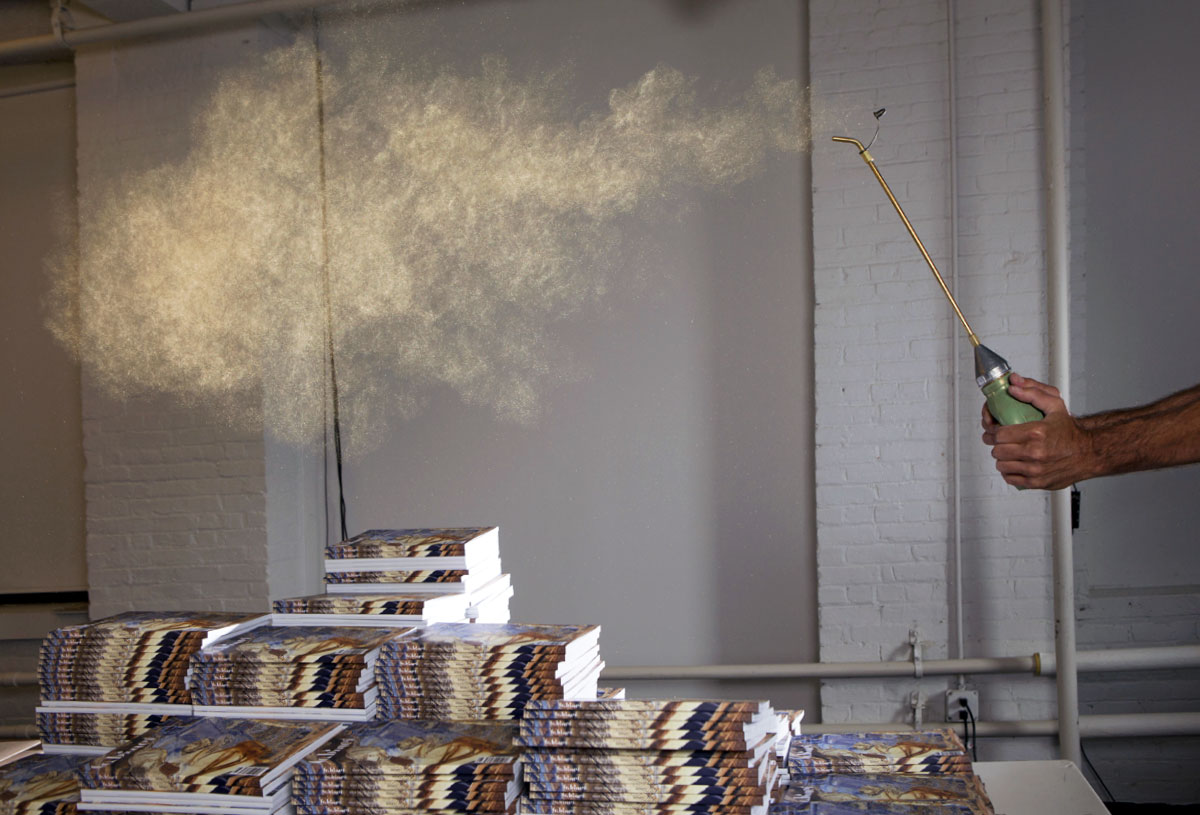 A photograph of piles of Cabinet’s new issue being sprinkled with gold dust by artist Peter Simensky.