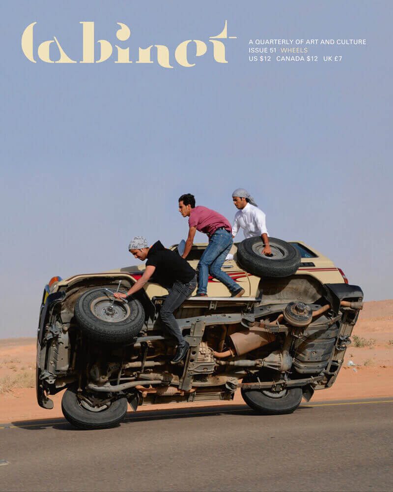 Photograph of Saudi Arabian men changing the tires on one side of their SUV while “sidewall surfing.”