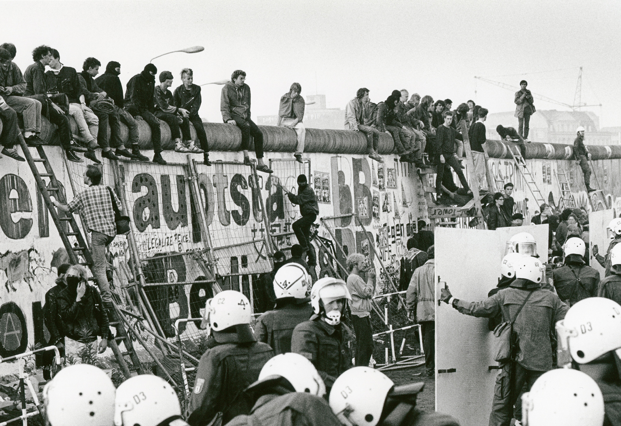 A photograph of protesters being met with police as they climbed the wall into East Berlin on the 1st of July nineteen eighty-eight.