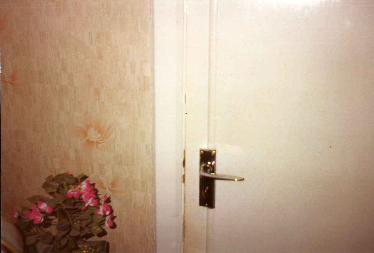 A photograph by Vera Merriman of a hallway and a closed door.