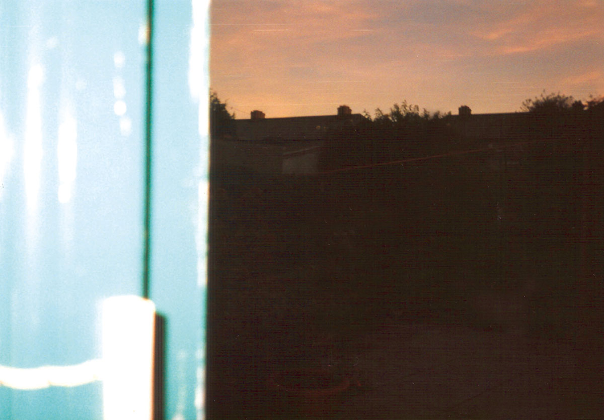 A blurred photograph by Vera Merriman of her back yard, and neighboring houses.