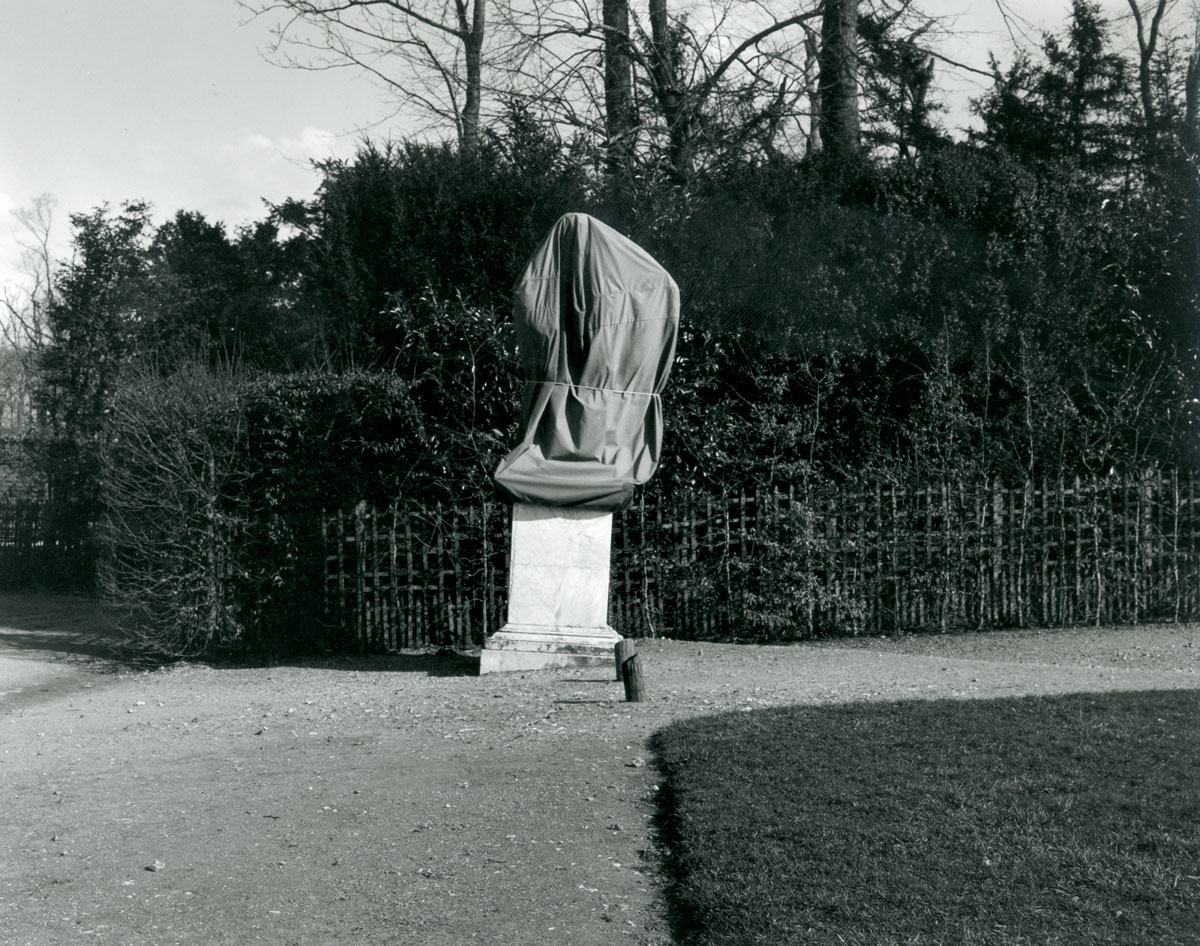 A 2001 photograph by artist Ann Burke Daly from her series “Anti-Monuments” depicting a sculpture in the gardens of Versailles covered with a tarp.