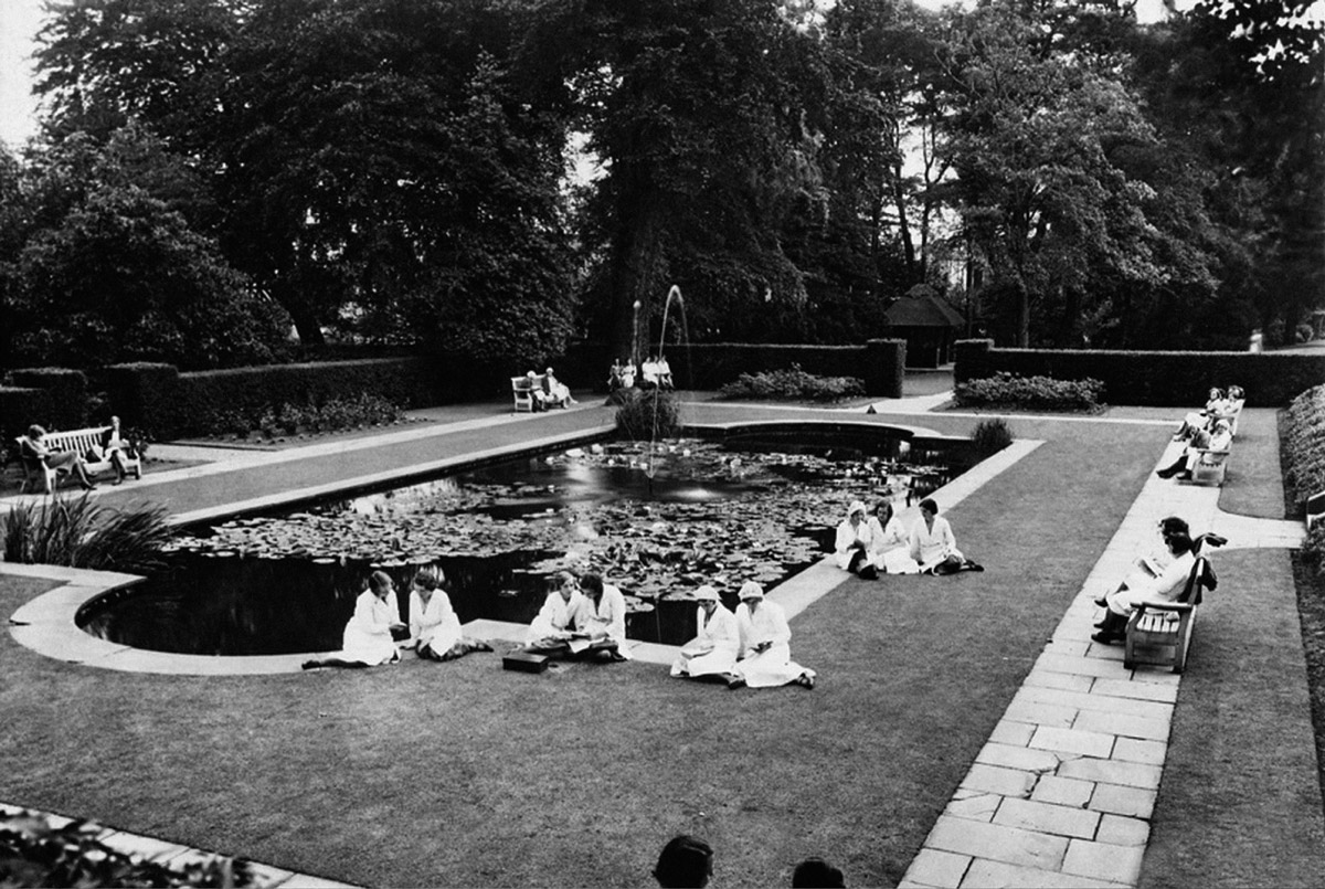 A nineteen thirty two image of workers at Cadbury’s factory in Bournville taking a break at a courtyard pond during a heat wave.