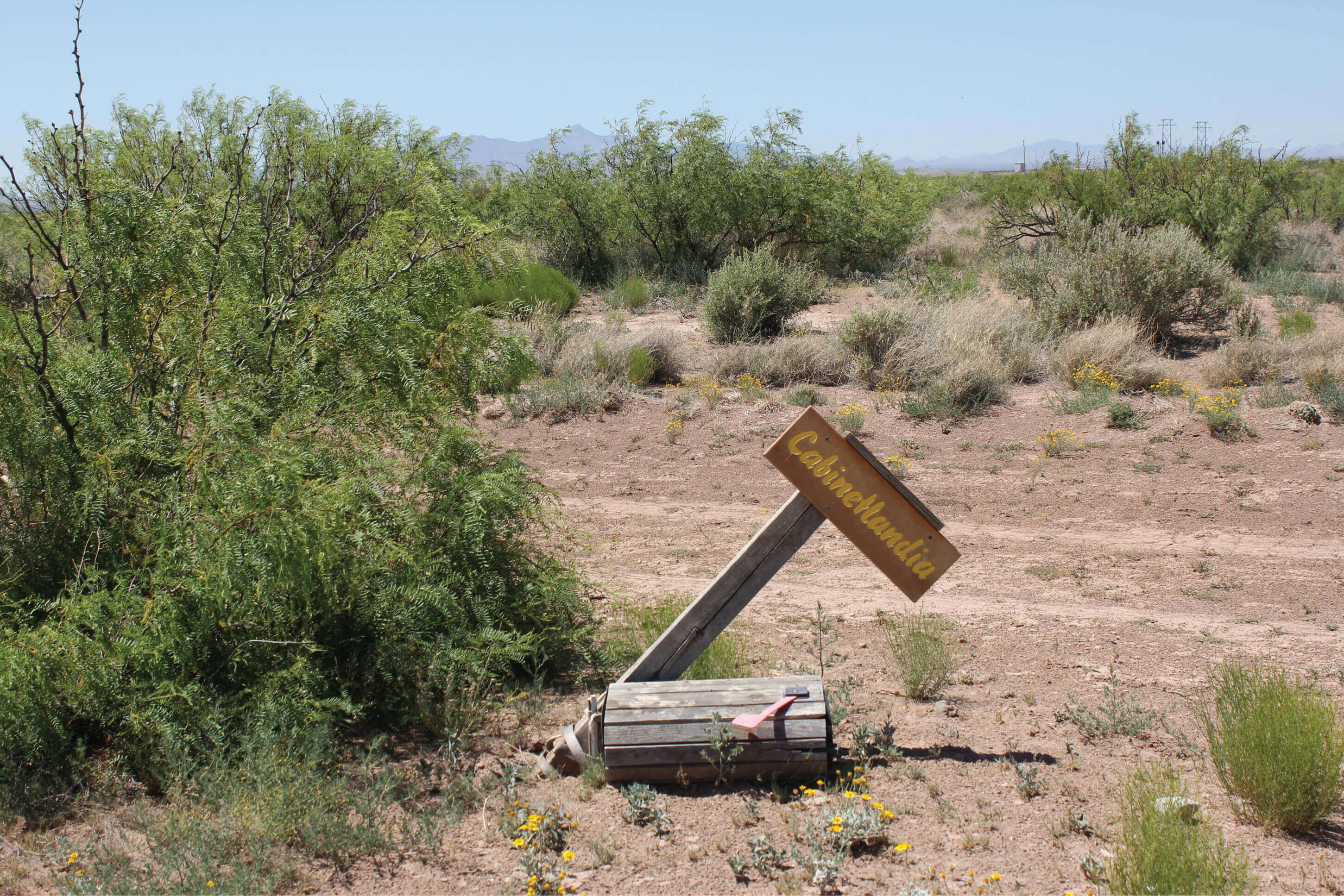A photograph of a weathered “Cabinetlandia” sign in the desert.