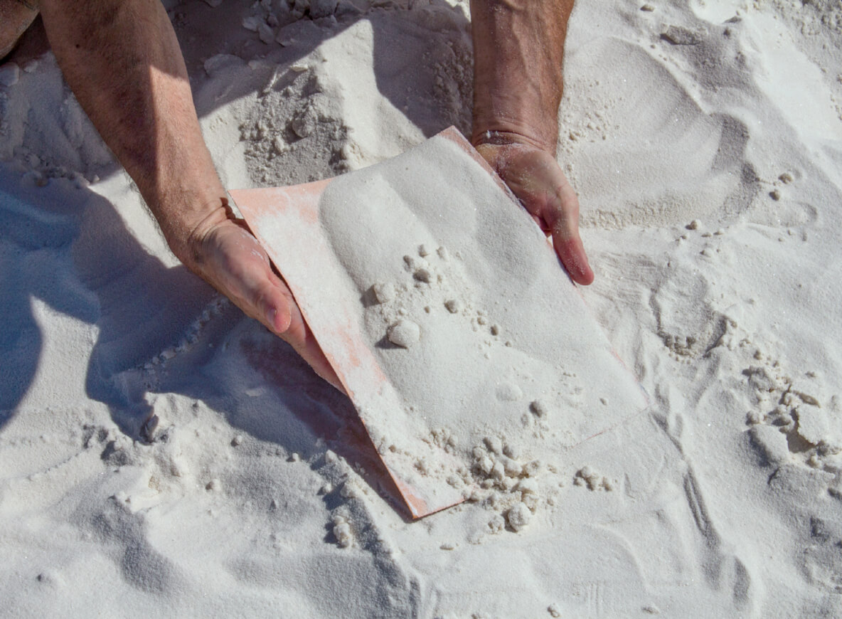 A photograph of a person collecting sand in White Sands, New Mexico.